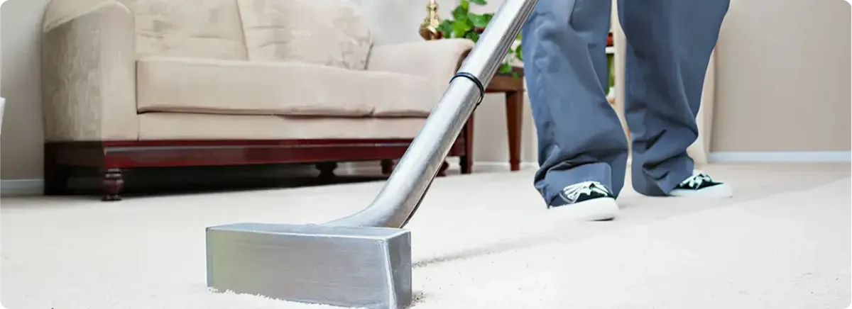 Carpet cleaning technician using a hot-water extraction wand on a light-colored carpet in a living room, Mesa, AZ.