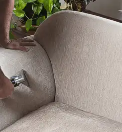 Professional upholstery cleaner deep-cleaning a fabric sofa with a handheld extraction tool and hose Mesa, AZ.